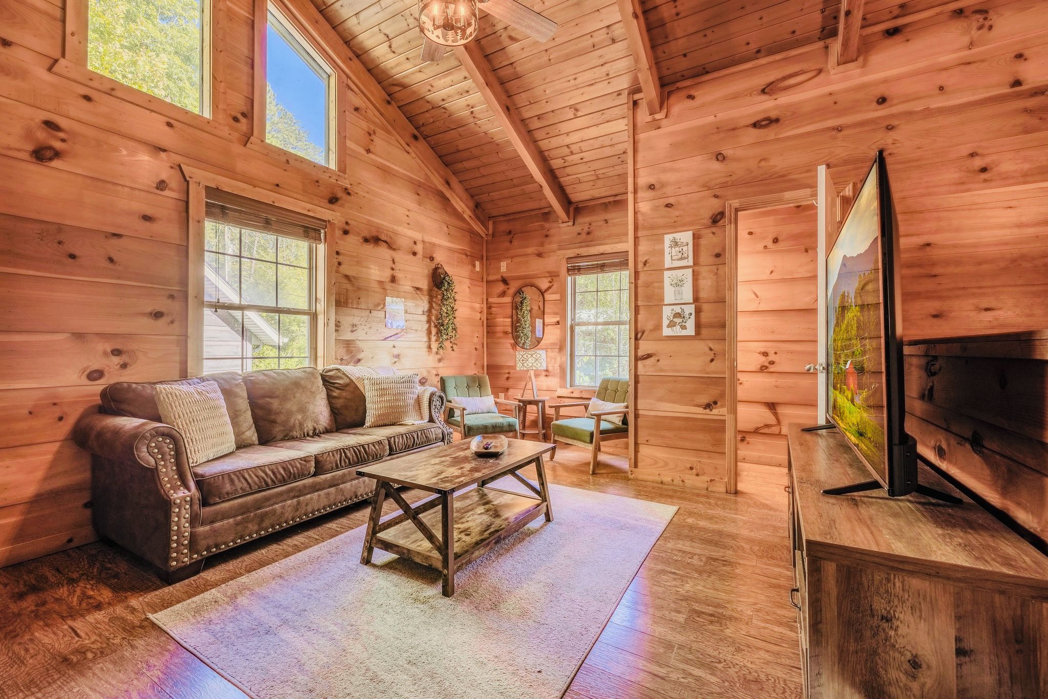 A cozy cabin interior with a sofa, coffee table, and television.