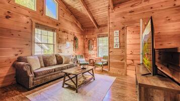 A cozy cabin interior with a sofa, coffee table, and television.