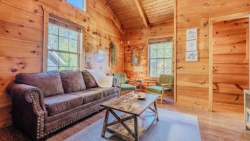 A cozy cabin interior with a leather sofa, a wooden coffee table, and a green armchair.