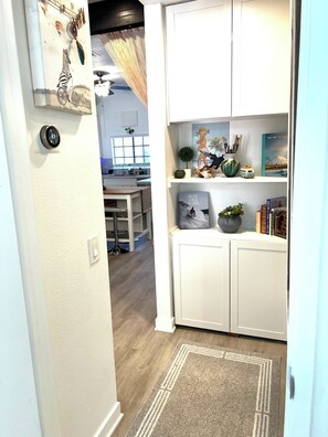 A hallway with a white door, a wall-mounted thermostat, and a small plant. - A Little Coastal Living_ Carlsbad Staycation (Carlsbad)