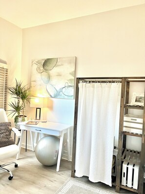 A room with a desk, chair, exercise ball, potted plant, and a large abstract painting on the wall. - A Little Coastal Living_ Carlsbad Staycation (Carlsbad)