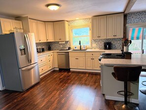 A kitchen with white cabinets, a stainless steel refrigerator, a coffee maker, and a window with a view. - Jamesville Luxury Retreat Pool, Hot Tub & 4BR (Jamesville)