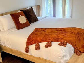 A bed with white bedding, a brown throw blanket with tassels, and two pillows with a pumpkin design. - Jamesville Luxury Retreat Pool, Hot Tub & 4BR (Jamesville)