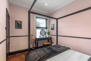 A bedroom with a bed, a desk, a window with blinds, and a potted plant. - The Tri-House (Watford)