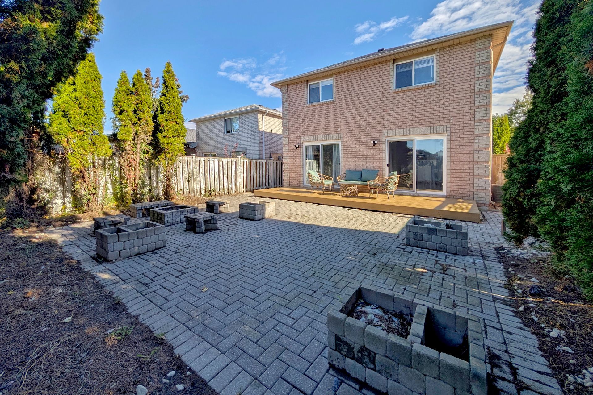 A two-story brick house with a paved patio and outdoor seating area.