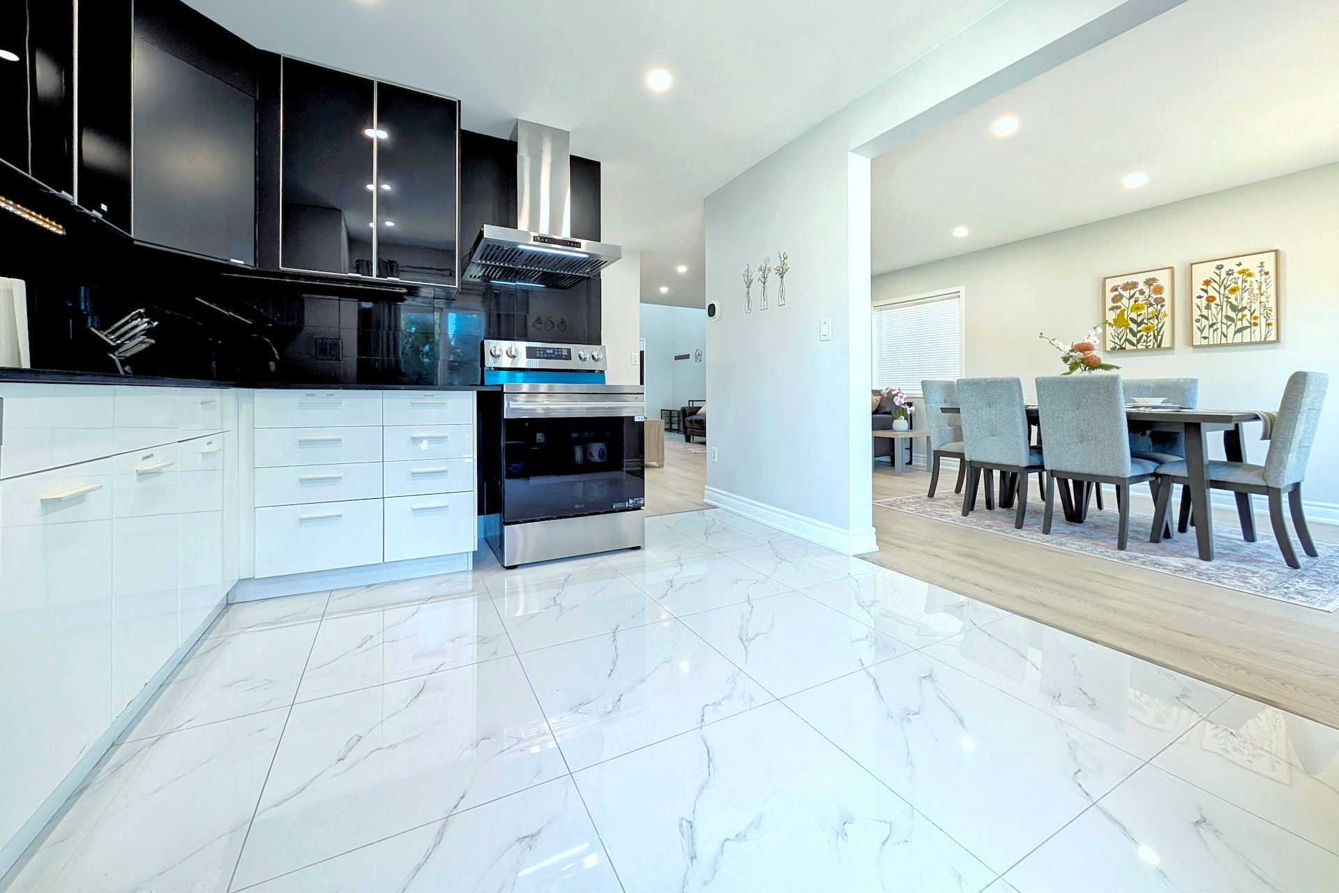 A modern kitchen with white cabinetry, a built-in oven, and a dining area with a table and chairs.