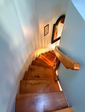 A wooden staircase with a handrail, leading to a landing with a framed picture. - Shell House - A One-of-a-Kind Stay (Mangōnui)