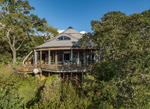 A wooden house with a balcony, surrounded by dense greenery. - Shell House - A One-of-a-Kind Stay (Mangōnui)