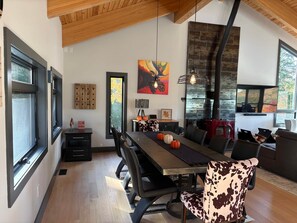 A modern dining area with a long table, chairs, and a fireplace. - Shimmering Peaks Retreat (Thornton)