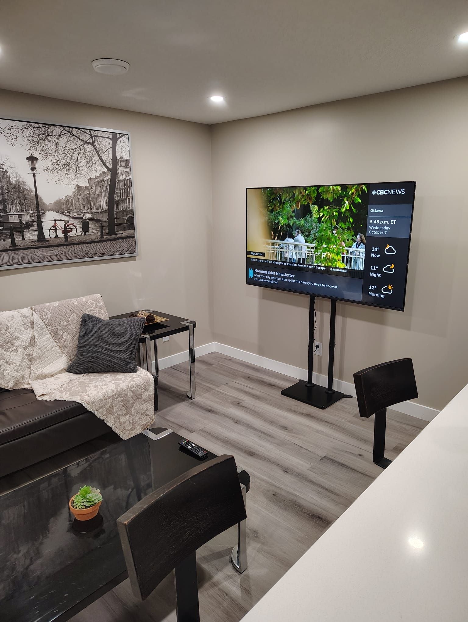 Una sala de estar moderna con un televisor de pantalla plana montado en la pared, un sofá, una mesa de centro y una mesa de comedor con sillas.