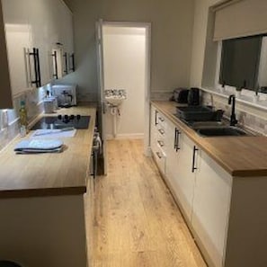 A compact kitchen with a wooden countertop, a sink, and cabinets. - Central Darlington - House - Parking - Sleeps 5 (Darlington)