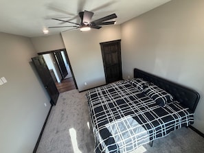 Une chambre à coucher avec un lit, un ventilateur de plafond et une porte donnant sur une autre pièce.