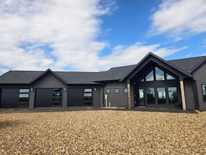A modern building with a large garage, a covered entryway, and a gravel driveway.