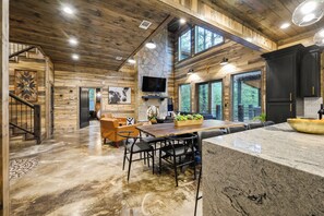 A spacious kitchen with a large island, stone accents, and a stone fireplace. - Hot Tub | Game Room | Playset | Patio Oasis! (Broken Bow)