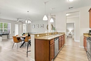 A spacious kitchen with a central island, wooden cabinets, and a dining area with chairs. - Vista Cay 3BR Near Universal & Epic Universe (Orlando)