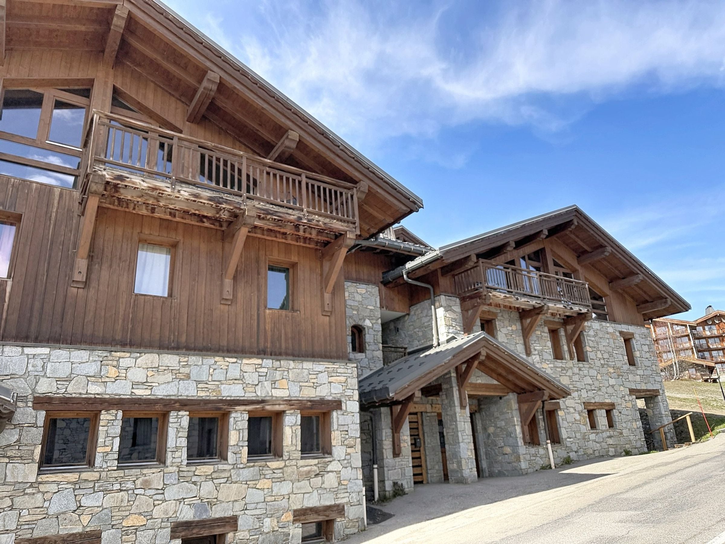 A wooden chalet with stone walls, balconies, and a stone entrance.