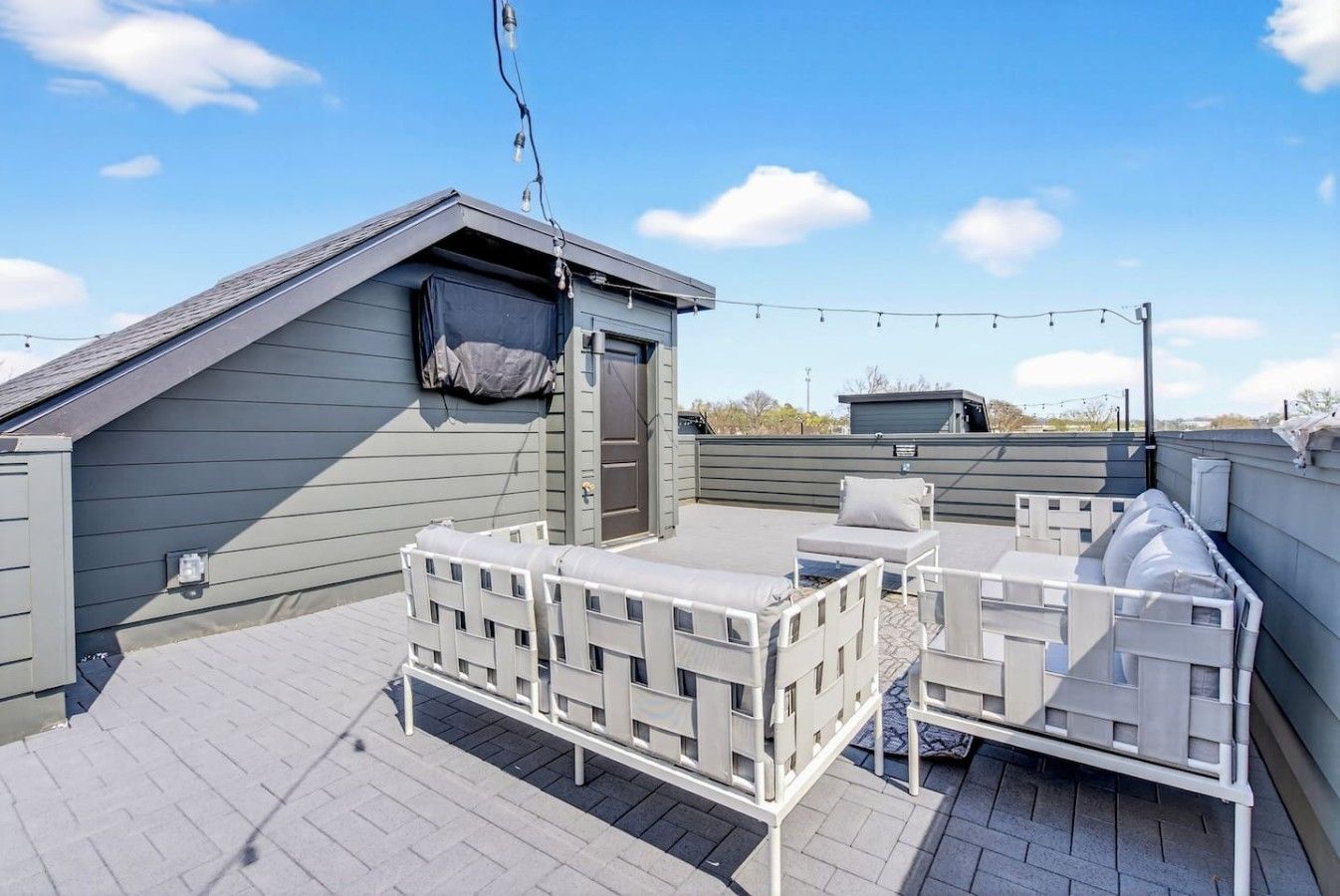 A rooftop terrace with a covered seating area, a small enclosed space, and string lights.