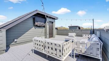 A rooftop terrace with a covered seating area, a small enclosed space, and string lights.