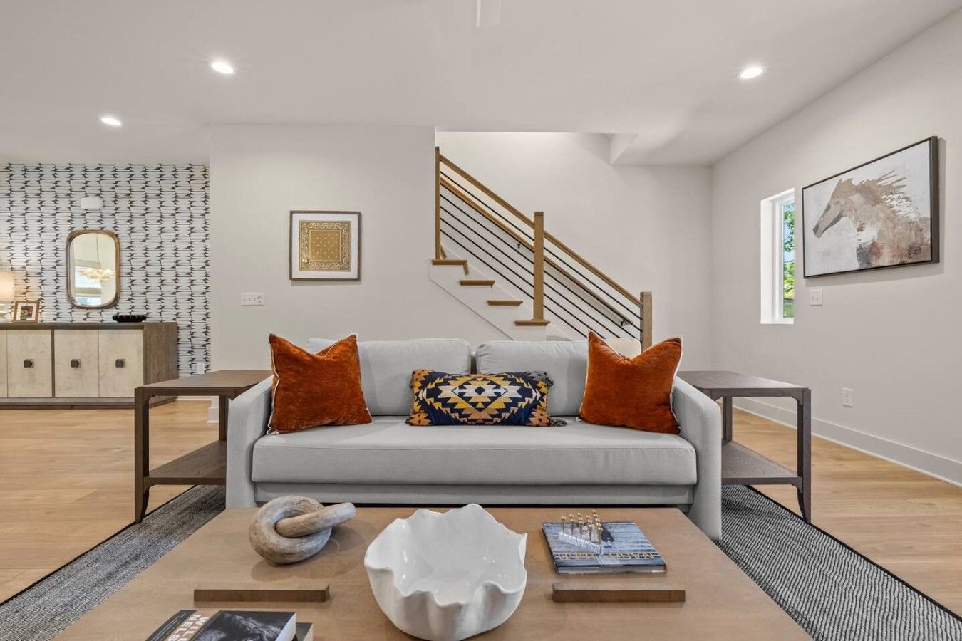 A modern living room with a grey sofa, wooden coffee table, and a staircase.