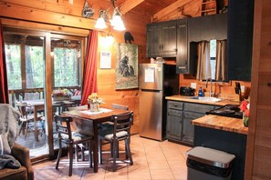 A cozy cabin interior with a dining area, kitchen, and a large window. - 47 Bear Ridge cozy 2 bedroom 1 bathroom cabin. Perfect getaway (Sautee)