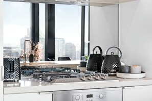 A modern kitchen with a gas stove, a coffee maker, and a kettle on the counter. - Skyline Noir City Views near Melbourne Highlights (Melbourne)