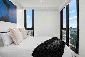 A modern bedroom with a large bed, two windows, and a city view. - Skyline Noir City Views near Melbourne Highlights (Melbourne)