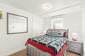 A bedroom with a bed, bedside table, lamp, and a window with blinds. - Cozy Salina Home w Patio, Yard & Full Kitchen! (Salina)