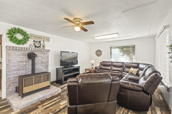 A living room with a fireplace, leather recliner, flat-screen TV, and a ceiling fan. - Cozy Salina Home w Patio, Yard & Full Kitchen! (Salina)