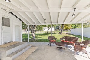 A covered patio with concrete flooring, two wicker chairs with cushions, and a white door. - Cozy Salina Home w Patio, Yard & Full Kitchen! (Salina)