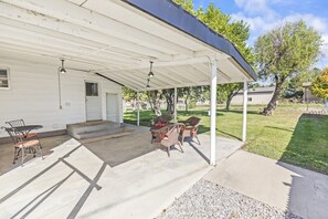 A covered patio with outdoor furniture, a concrete floor, and a white building in the background. - Cozy Salina Home w Patio, Yard & Full Kitchen! (Salina)