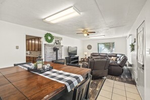 Un amplio espacio habitable con chimenea, una mesa de comedor y una zona de estar con un sillón reclinable.