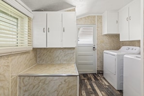 A laundry room with a door, white cabinets, and a washing machine. - Cozy Salina Home w Patio, Yard & Full Kitchen! (Salina)
