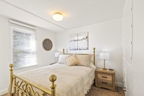 A bedroom with a bed, bedside tables, a wall clock, a window with blinds, and a ceiling light. - Cozy Salina Home w Patio, Yard & Full Kitchen! (Salina)