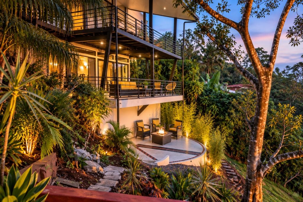 Une maison moderne dotée d’un balcon, d’un espace salon extérieur et d’un foyer.