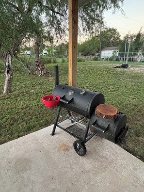 A portable barbecue grill with a red bowl and a wooden log on a concrete surface. - Private Room in Brandnew Home. Fullsize Bathroom & Kitchen. 5min from Airport (Harlingen)