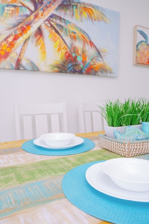 A dining area with a table set for two, a colorful painting on the wall, and a potted plant. - Beachside Escape at the Gulfplace with Pools, Hot Tubs and Fine/Casual Dinning (Santa Rosa Beach)