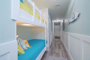 A bunk bed room with a blue mattress, white walls, and a hallway leading to a door. - Beachside Escape at the Gulfplace with Pools, Hot Tubs and Fine/Casual Dinning (Santa Rosa Beach)