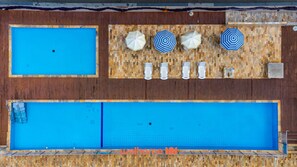Une piscine sur le toit, divisée en deux zones distinctes, entourée d’une terrasse en bois et agrémentée d’un mur recouvert de mosaïques.