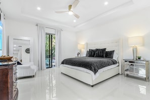 Une chambre à coucher moderne avec un grand lit, un ventilateur de plafond et une table de chevet avec une lampe.