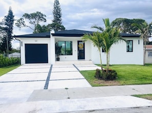 A modern two-story house with a garage, a front porch, and a well-maintained lawn. - Perfect 4-bedroom house with AC in charming Naples (Naples)