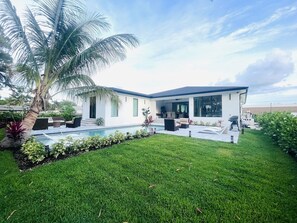 A modern house with a swimming pool, outdoor seating, and a well-maintained lawn. - Perfect 4-bedroom house with AC in charming Naples (Naples)