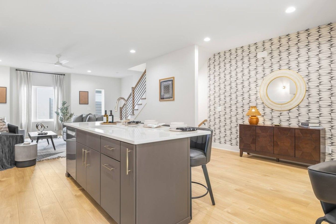 Une cuisine moderne dotée d’un îlot central, un coin repas avec une table et des chaises, et un espace de vie comprenant un canapé et une table basse.