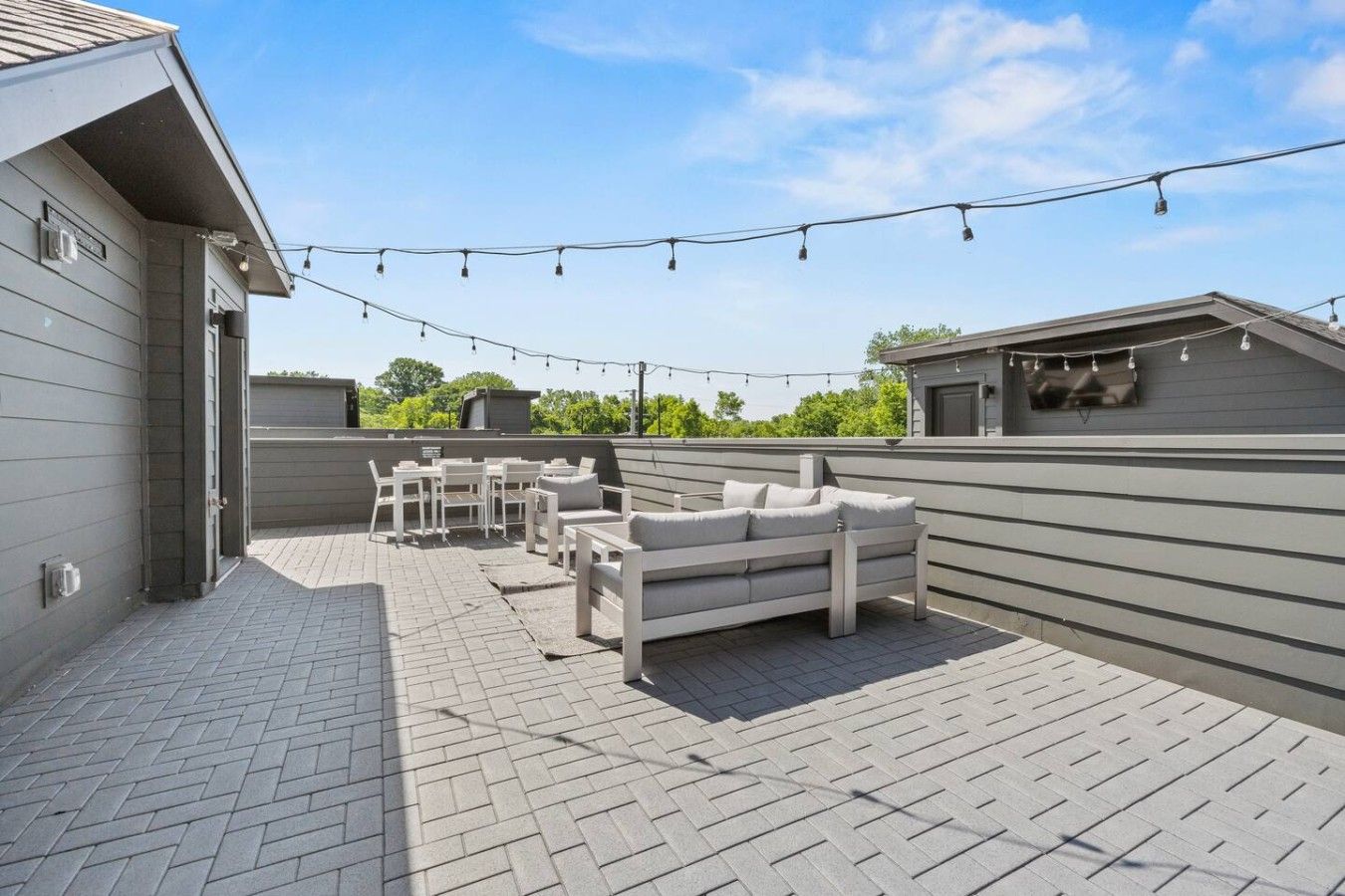 An outdoor patio with a seating area, string lights, and a view of the surrounding landscape.