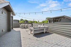 An outdoor patio with a seating area, string lights, and a view of the surrounding landscape. - Rooftop Deck with BBQ & TV, 3 Miles to Downtown, Garage (Nashville)