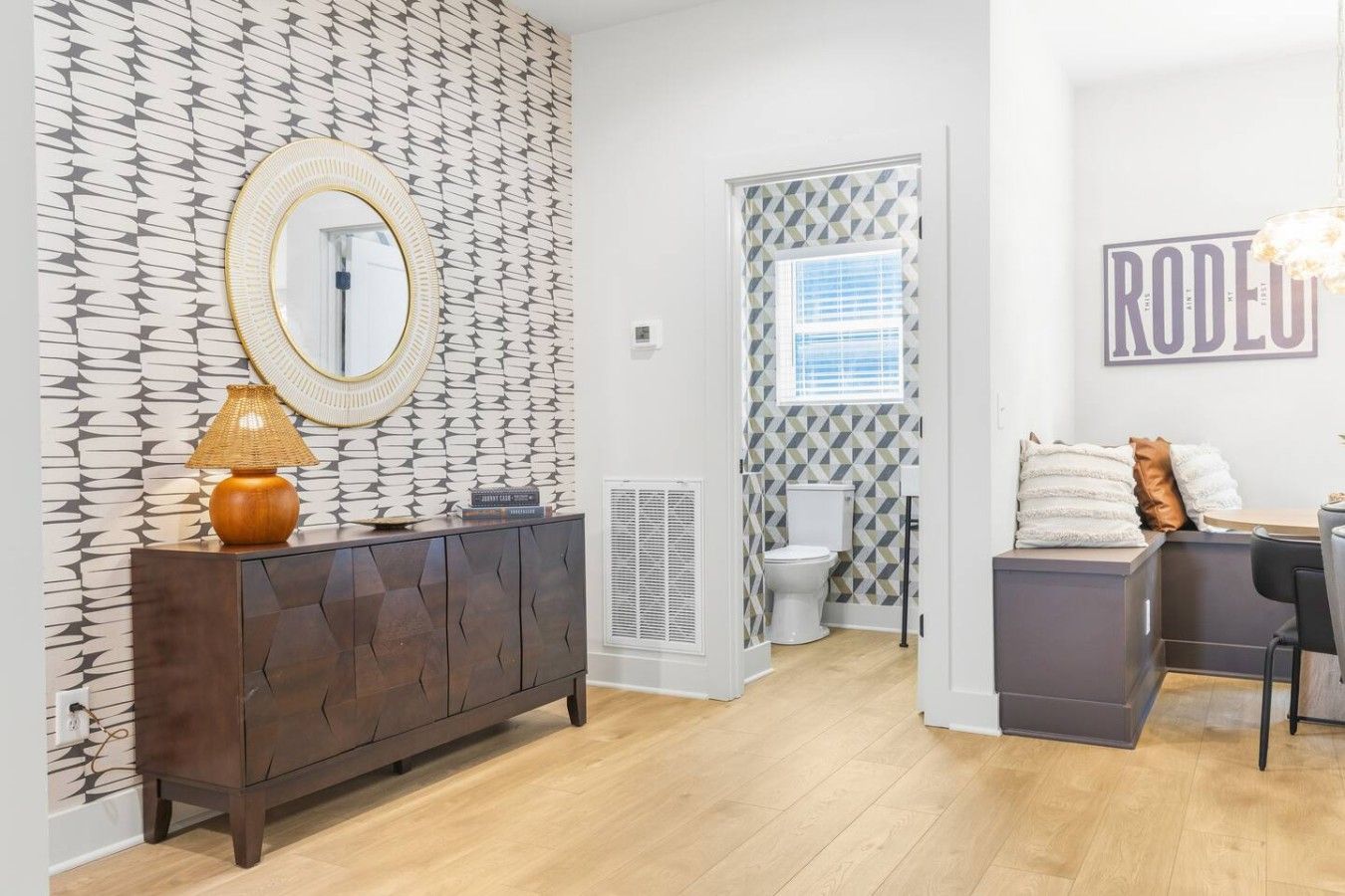 A modern bathroom with a patterned wall, a round mirror, a toilet, and a shower area.