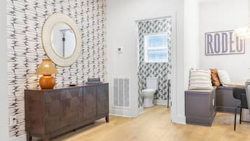A modern bathroom with a patterned wall, a round mirror, a toilet, and a shower area.