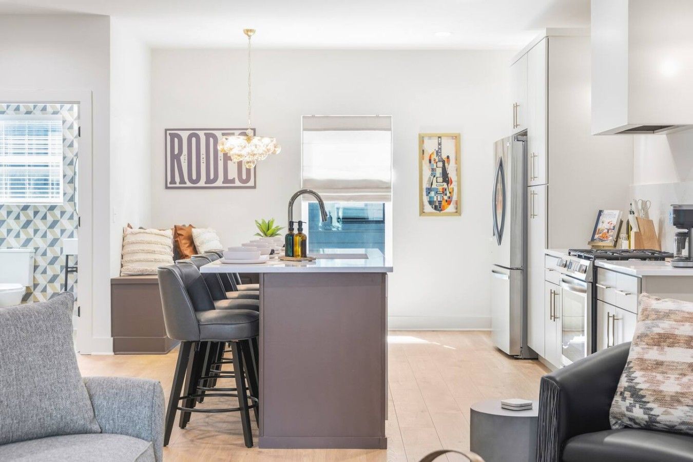 A modern kitchen with a central island, stainless steel appliances, and a dining area with bar stools.