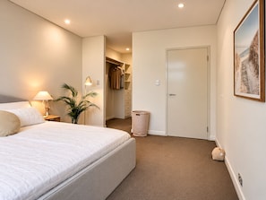 Een slaapkamer met een bed, een bedlampje en een plant in een pot.