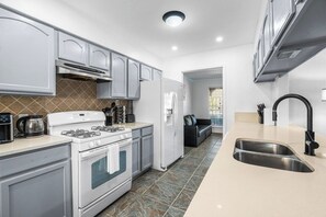 A modern kitchen with white appliances, a double sink, and a tiled backsplash. - Spacious 3BR w/ Fenced Yard, Near Austin Downtown (Austin)