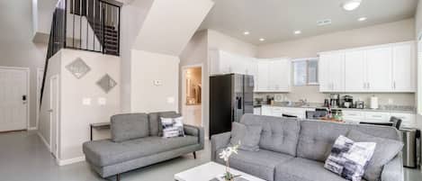 A modern apartment with a living room, kitchen, and staircase.